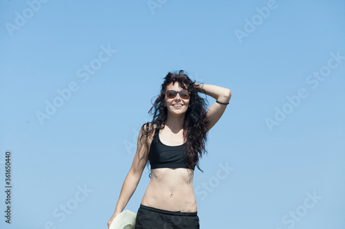 Wanderlust of a sporty and young woman The woman is on top of a mountain overlooking the peaks of the tramuntana in Majorca, The woman is wearing black trekking clothes, a hat and glasses. Summer 