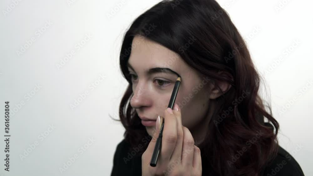 Young girl draws on a traditional makeup for the holiday of Santa Muerte. Theme of costumes and transformation for holiday of Halloween. Traditional skull makeup for the day of the dead celebration. Young girl draws on a traditional makeup for the holiday of Santa Muerte. Theme of costumes and transformation for holiday of Halloween. Traditional skull makeup for the day of the dead celebration.