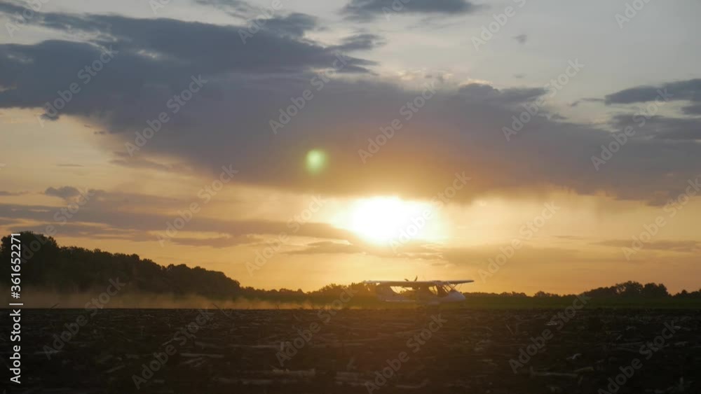 A small airplane takes off from a field.at sunrise A small airplane takes off from a field.at sunrise