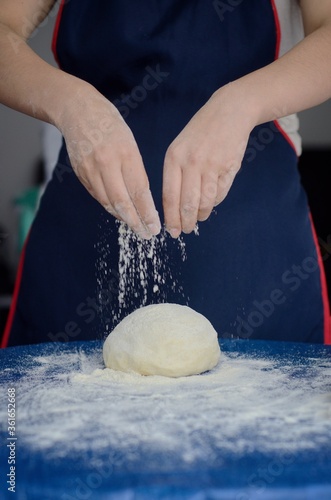 Mano de mujer rociando harina sobre la masa. Gastronomía y repostería. photo