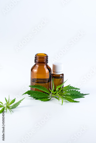 Fototapeta Naklejka Na Ścianę i Meble -  Medical, chemical theme background with cannabis leaves, oil bottle and young marijuana plant in a pot behind.