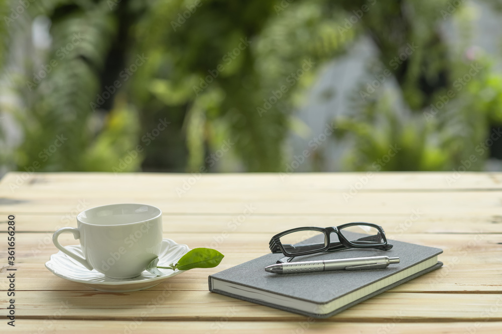 cup of coffee with diary, pen and eyeglasses on a wooden table with blurred background cup of coffee with diary, pen and eyeglasses on a wooden table with blurred background