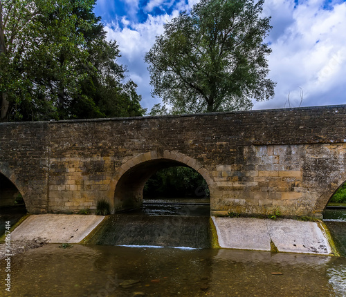 A view of an arch in the bridge over the River Ise in the town of Geddington, UK in summer photo