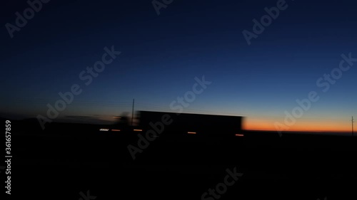 Driving POV on a highway at dawn with passing trucks