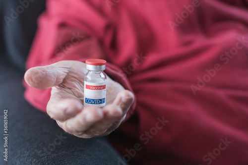coronavirus vaccine vial in elderly person's hand