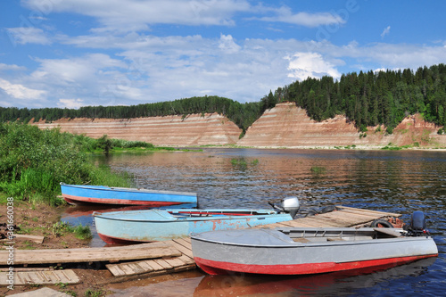 three boats are moored on the river Bank.High Bank, rocky, steep. Exposed geological rock, which is more than 200 million years old. Quiet, Calm. Tourist area. Summer.The photo is horizontal.