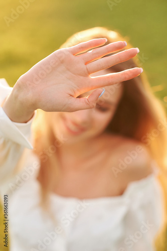 Young pretty woman natural outdoor portrait. Beautiful girl trying to cover camer with her hand
