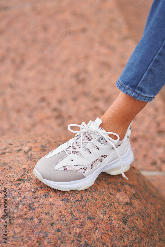 Closeup of woman feet and white sneakers. Casual dressed girl. Outdoor shot. Fashion casual image