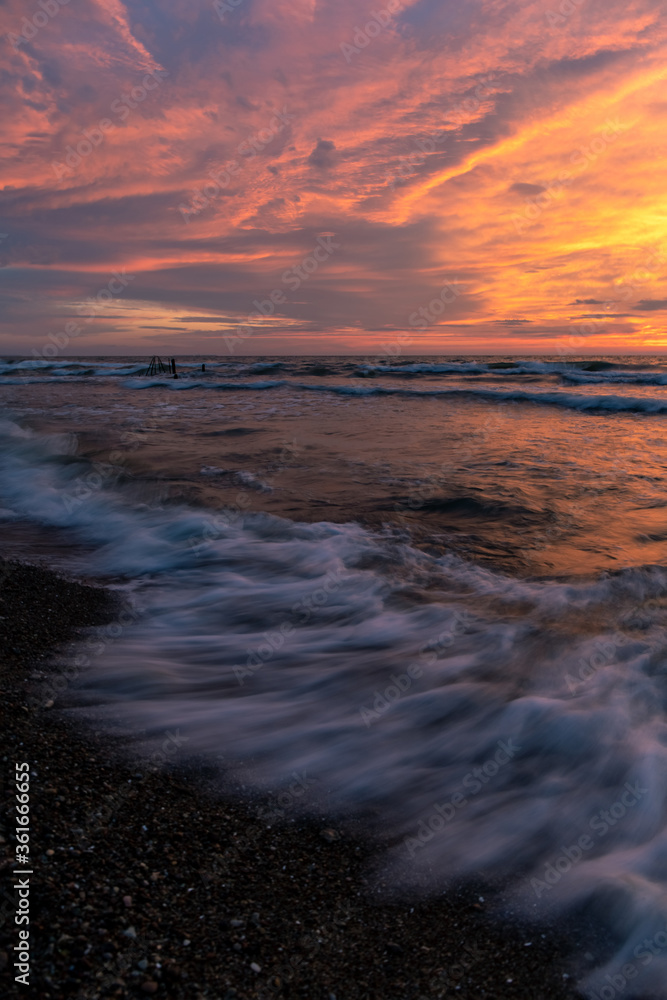 bright picturesque sunset by the sea with a blurry wave