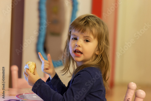 Obraz na płótnie a little girl eating a donut w salonie