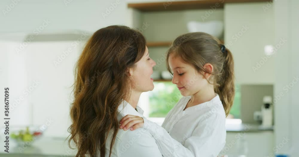 Authentic shot of an young happy smiling mother is enjoying time together with her cute little girl in the kitchen. A daughter giving hug to a mother, they are happy to spend time together. Authentic shot of an young happy smiling mother is enjoying time together with her cute little girl in the kitchen. A daughter giving hug to a mother, they are happy to spend time together.
