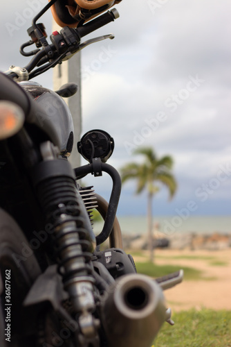 Focused view of a shiny black fuel tank on an antique motorcycle at the beach