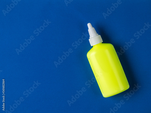 Yellow bottle with a white cap on a blue background.
