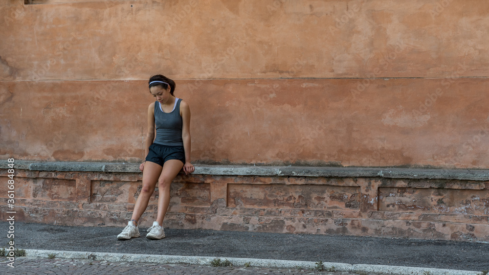 Young teen girl with headband, shorts, tanktop and sneakers sitting on brick bench Young teen girl with headband, shorts, tanktop and sneakers sitting on brick bench