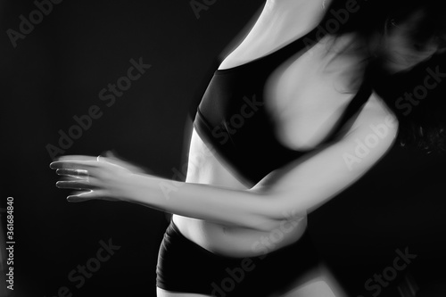 Spiritual dance. Transcendent energy. Blur woman silhouette performing sensual movement isolated on black.