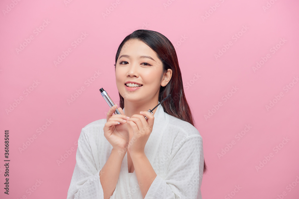 Young attractive woman with dark hair in white bathrobe holding mascara in hand playfully Young attractive woman with dark hair in white bathrobe holding mascara in hand playfully
