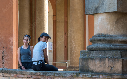 Asian woman sitting on wall with teen daughter standing next to her