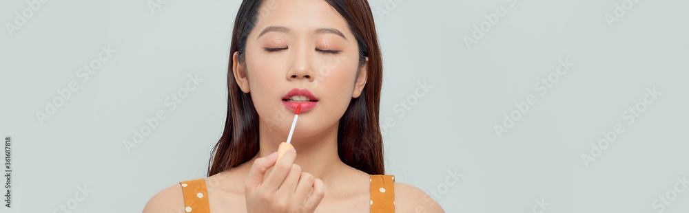 Close up portrait of a beautiful young woman with make up artist applying lip gloss Close up portrait of a beautiful young woman with make up artist applying lip gloss