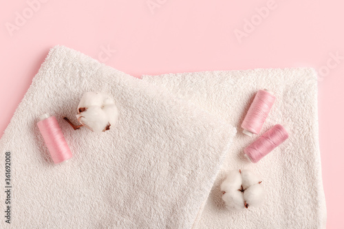 Cotton flowers, threads and soft towels on color background © Pixel-Shot