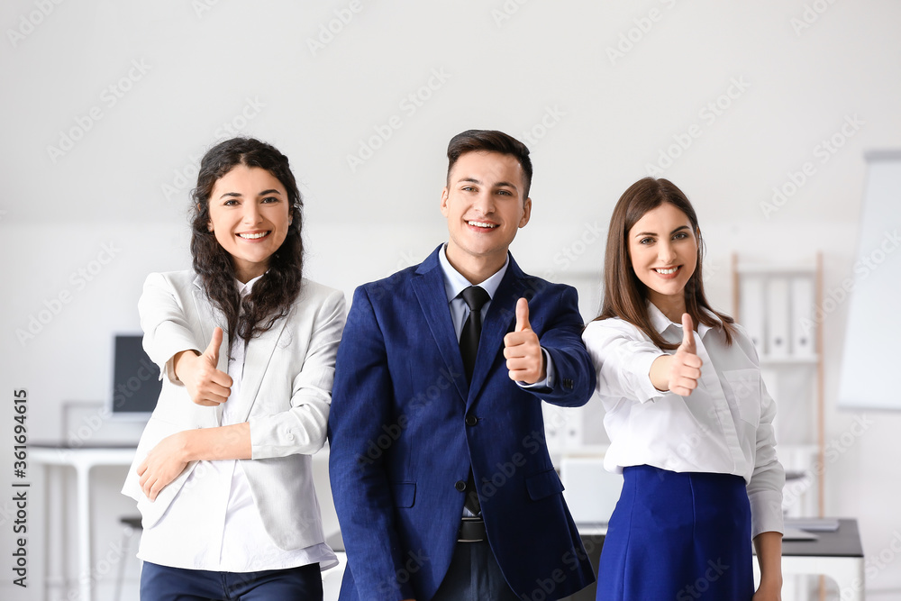 Young business people showing thumb-up gesture in office Young business people showing thumb-up gesture in office