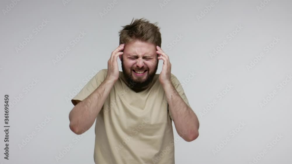 Flu-sick bearded guy rubbing temples clutching head to relieve pain, feeling unwell suffering headache, severe migraine, stress tension, fever and influenza symptoms. indoor studio shot isolated Flu-sick bearded guy rubbing temples clutching head to relieve pain, feeling unwell suffering headache, severe migraine, stress tension, fever and influenza symptoms. indoor studio shot isolated