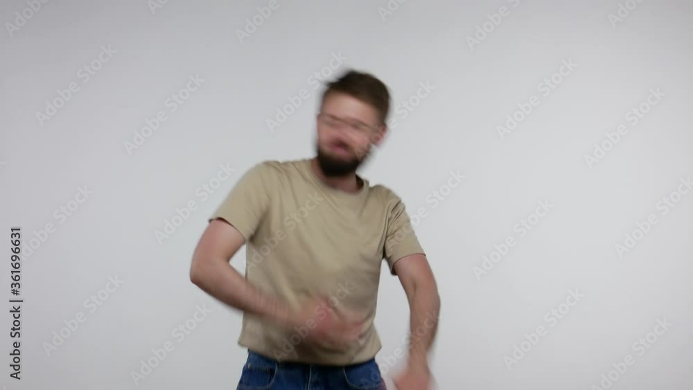 Carefree happy bearded man jumping dancing and singing, moving in quick dance rhythm while listening to favorite song, enjoying energetic vivid music. indoor studio shot isolated on gray background Carefree happy bearded man jumping dancing and singing, moving in quick dance rhythm while listening to favorite song, enjoying energetic vivid music. indoor studio shot isolated on gray background
