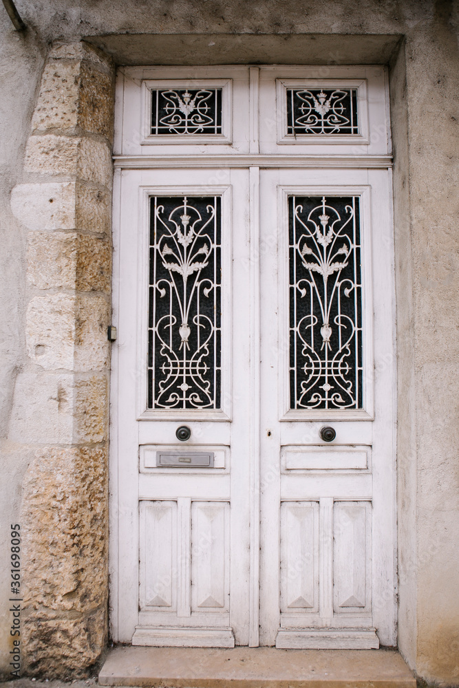 Old white wooden door with ornate windows in European village. Old white wooden door with ornate windows in European village.