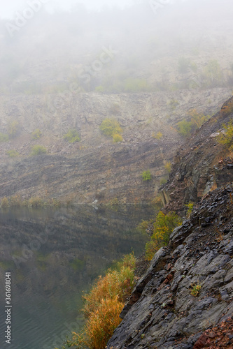 Landscape of lake in old flooded industrial granite quarry on a foggy autumn morning. Radon lake in Mygiya village, Ukraine photo