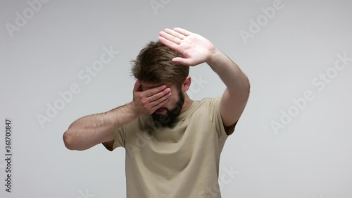 Don't want to look this! Displeased bearded man covering face and showing stop gesture, hiding eyes refusing to watch gross content, something shameful. indoor studio shot isolated on gray background