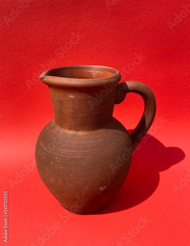 Clay brown vintage jug on a red background