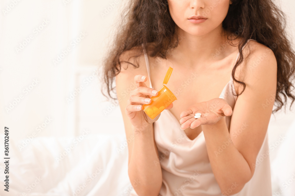 Young woman taking sleeping pills in bedroom Young woman taking sleeping pills in bedroom