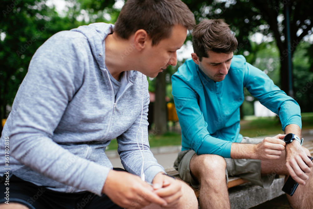 Fit young men taking rest from running. Two friends training outdoors. Fit young men taking rest from running. Two friends training outdoors.
