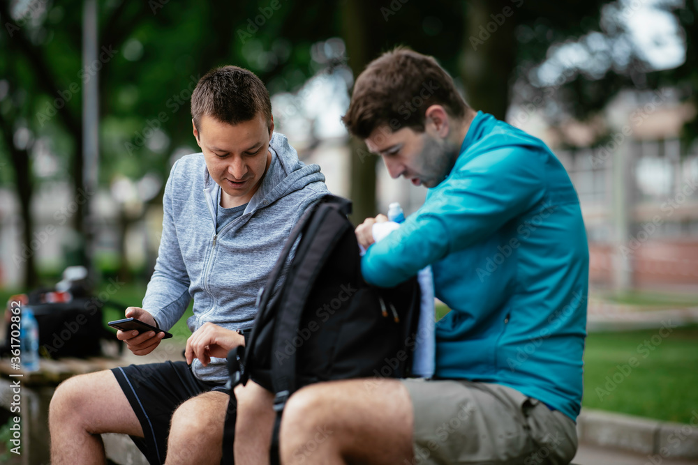 Fit young men taking rest from running. Two friends training outdoors. Fit young men taking rest from running. Two friends training outdoors.