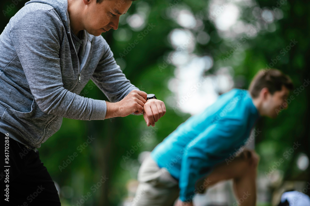 Young men exercising on a race track. Two young friends training outdoors. Young men exercising on a race track. Two young friends training outdoors.