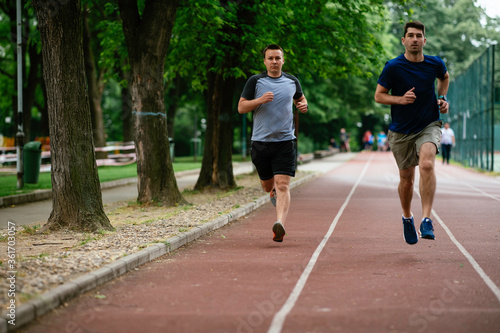Young men training on a race track. Two young friends running on the athletics track