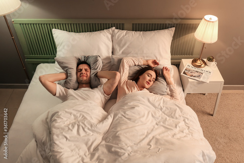 Young irritated man in bed ...