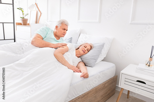 Mature irritated man in bed...