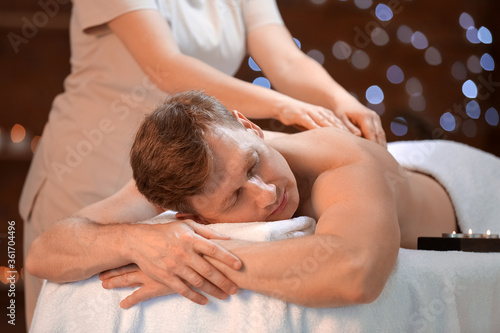 Handsome man receiving massage in spa salon