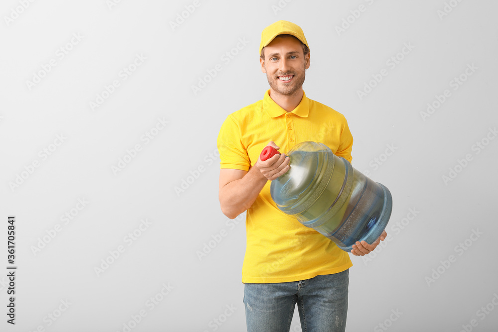 Delivery man with bottle of water on grey background
