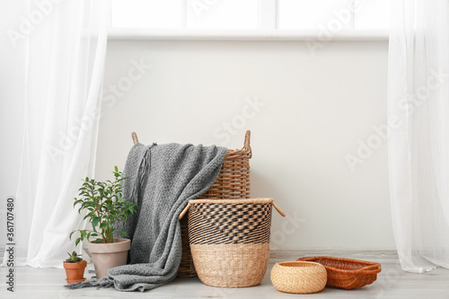 Wicker baskets with houseplants and plaid in room