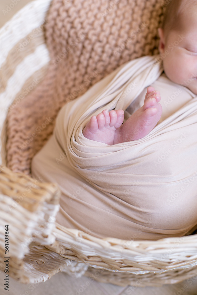 Cute little baby legs in a basket lies in a wicker basket in a beige knitted blanket. Summer mood. Happy healthy childhood Cute little baby legs in a basket lies in a wicker basket in a beige knitted blanket. Summer mood. Happy healthy childhood