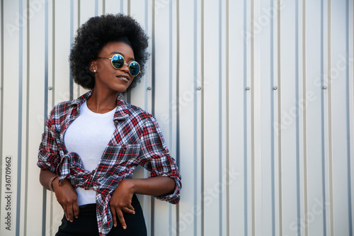People concept — african american young female wearing sunglasses with curly hair over grey background, copy space. Lifestyle.