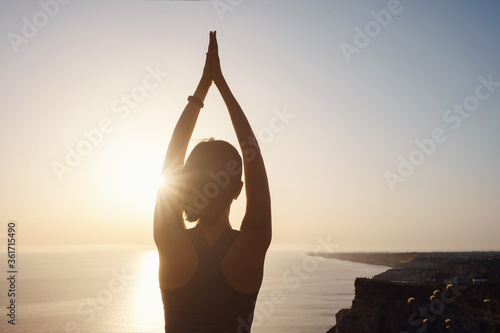 Young woman practicing yoga over sunset sea