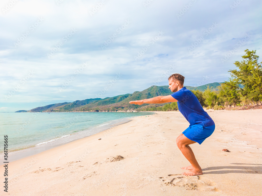 Young beautiful man doing sport performing workouts exercises near sea in the morning during quarantine. Active life without surgical sterilizing face mask protection Young beautiful man doing sport performing workouts exercises near sea in the morning during quarantine. Active life without surgical sterilizing face mask protection