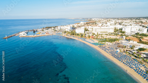 Aerial bird s eye view of Pantachou - Limanaki beach  Kaliva   Ayia Napa  Famagusta  Cyprus. Bay with golden sand  small fishing port  sunbeds  parasols  sea bar restaurants in Agia Napa  from above.