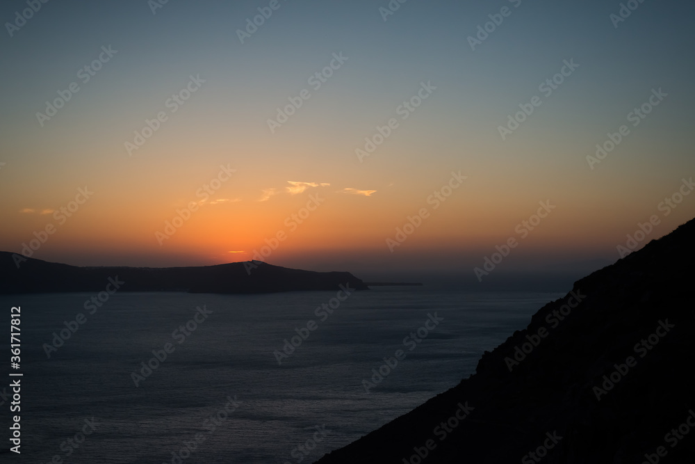 Sunset over the sea and the south end of the island of Santorini, Greece. View from Fira, the capital