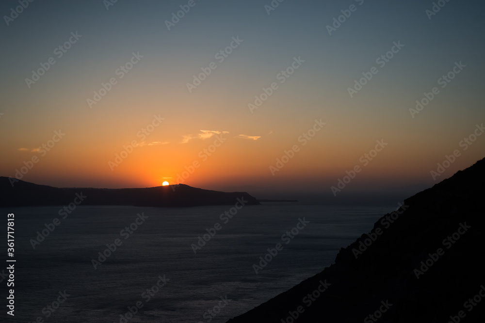 Sunset over the sea and the south end of the island of Santorini, Greece. View from Fira, the capital