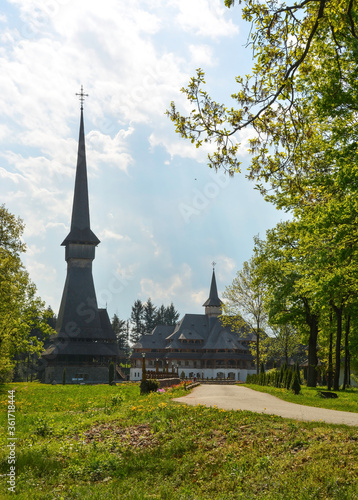 Obraz na płótnie Sapanta Peri Monastery, Maramures, Romania, Europe, spring 2018. Traditional wooden church with the tallest bell tower in the world. Maximum height of 78 meters. Surrounded by vegetation w salonie