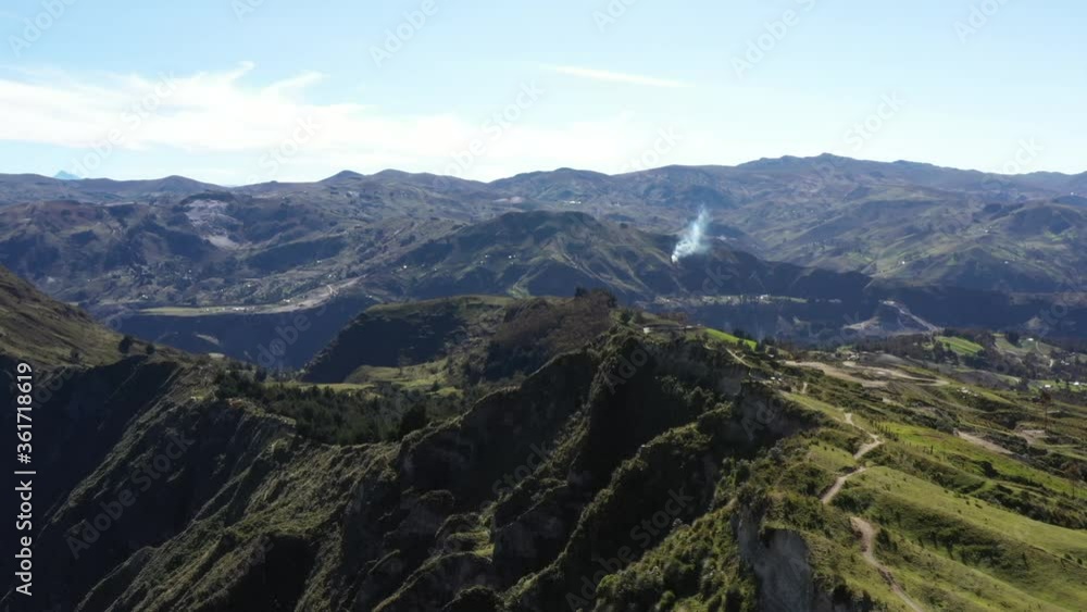 Aerial view flying over a walking track on the top of a large hill with a mountanous background and a smoke of a large fire visible
Aerial view flying over a walking track on the top of a large hill with a mountanous background and a smoke of a large fire visible