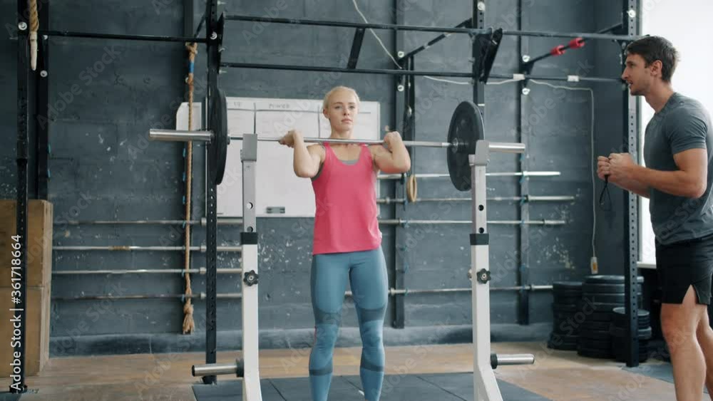 Pretty girl is lifting weight in gym while man trainer is motivating student talking gesturing enjoying personal training with woman. People and sports concept. Pretty girl is lifting weight in gym while man trainer is motivating student talking gesturing enjoying personal training with woman. People and sports concept.